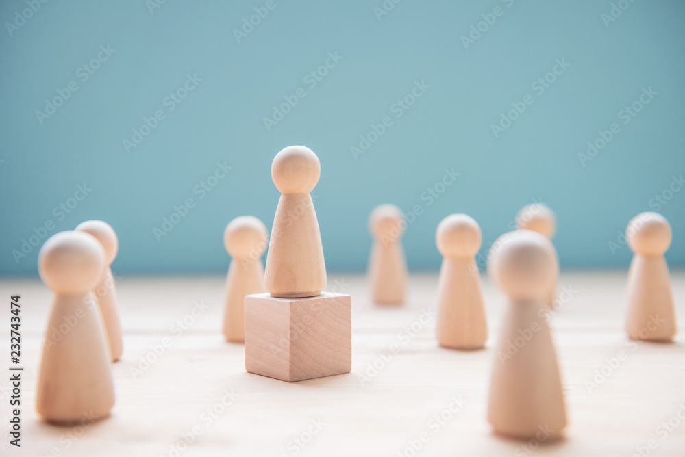 Leadership concept. Wood person model among people on blue background. Leadership concept. Wood person model among people on blue background.