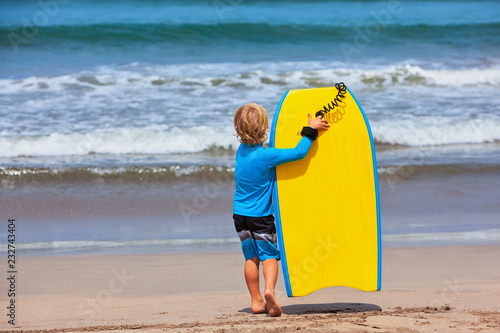 Tableau sur toile Baby boy - little surfer run with bodyboard to sea for riding on waves
