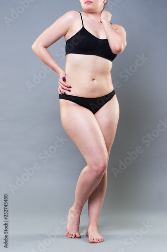 Woman in black underwear on gray background, cellulite on female body