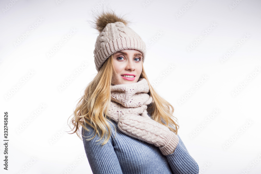 Portrait of beautiful young blonde woman wearing warm knitted sweater, hat, scarf and mittens on white background Portrait of beautiful young blonde woman wearing warm knitted sweater, hat, scarf and mittens on white background