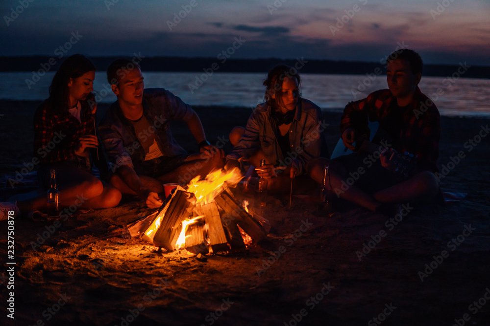 Camp on the beach. Group of young friends having picnic with bonfire Camp on the beach. Group of young friends having picnic with bonfire