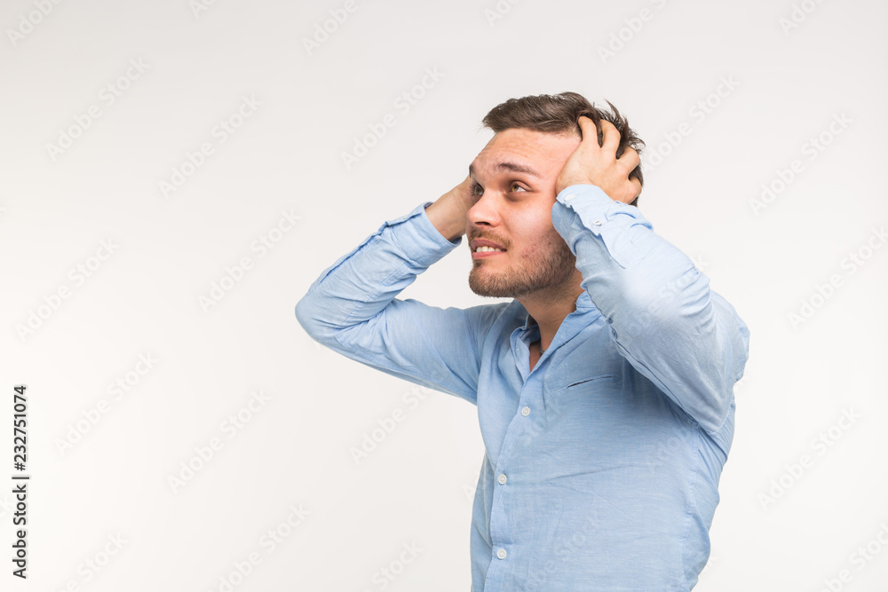 Expressions and people concept - Portrait of a young bearded man holding hands at his head isolated over white background Expressions and people concept - Portrait of a young bearded man holding hands at his head isolated over white background
