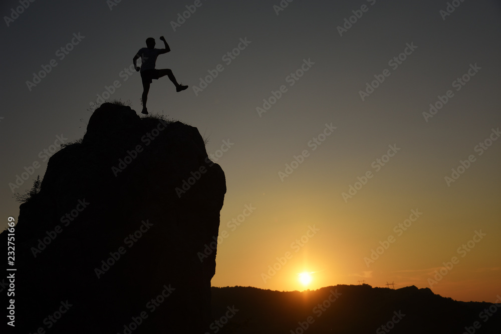 Successful man jumping on the edge of the cliff. Man jump on top of the mountain