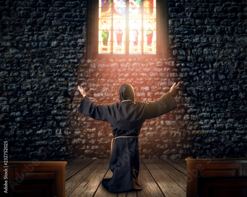 Medieval monk kneeling and praying in church