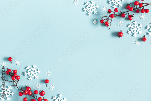 Christmas or winter composition. Frame made of snowflakes and red berries on pastel blue background. Christmas, winter, new year concept. Flat lay, top view, copy space