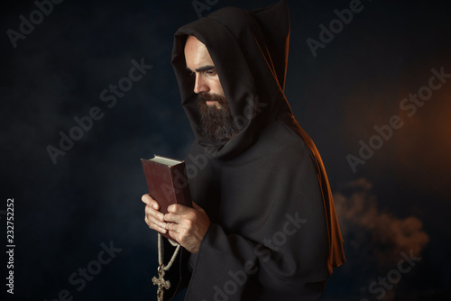 Fototapeta Medieval monk praying with book and cross in hands