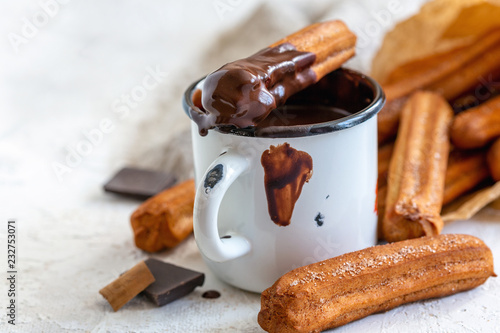 Churros with cinnamon in mug of hot chocolate.