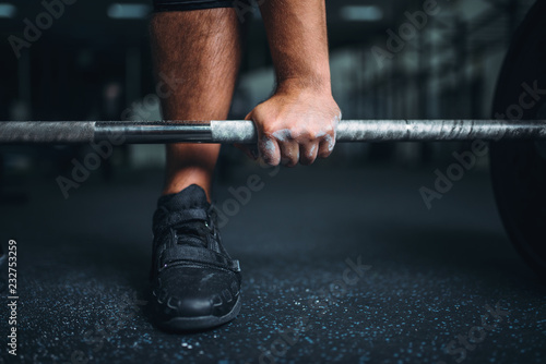 Powerlifter prepares for deadlift a barbell in gym