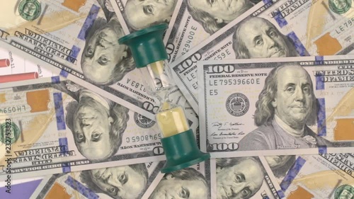 Rotation of the hourglass lying on the dollars.