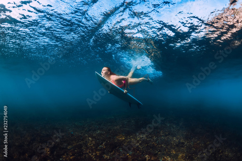 Sporty surfer woman dive underwater with under wave.