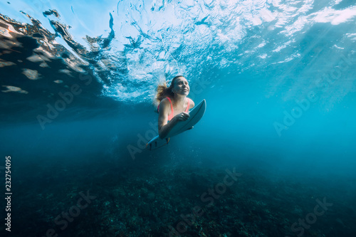 Attractive surfer woman in bikini with surfboard dive underwater with under barrel wave