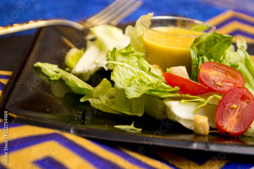 Lettuce salad set on plate with small cup of dressing
