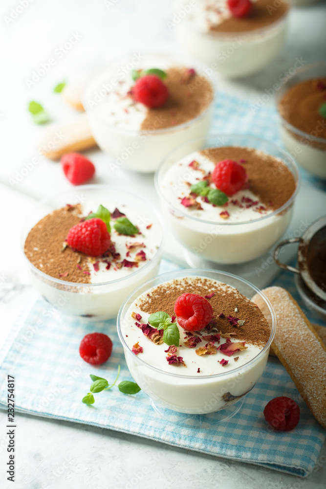 Homemade tiramisu dessert decorated with fresh raspberry and rose petals Homemade tiramisu dessert decorated with fresh raspberry and rose petals