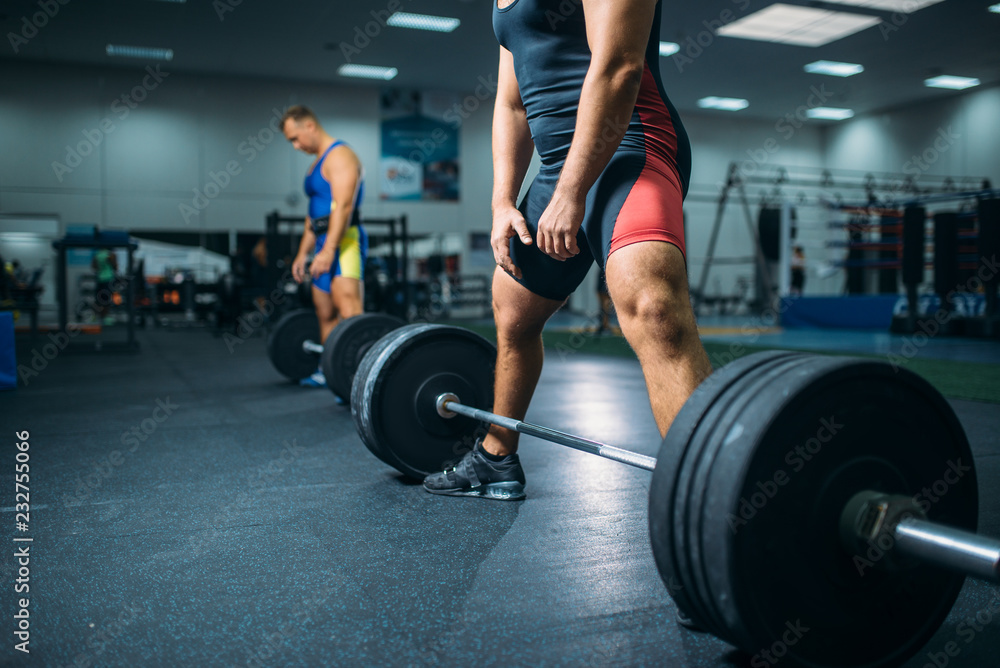 Two weightlifters doing exercise with barbells Two weightlifters doing exercise with barbells