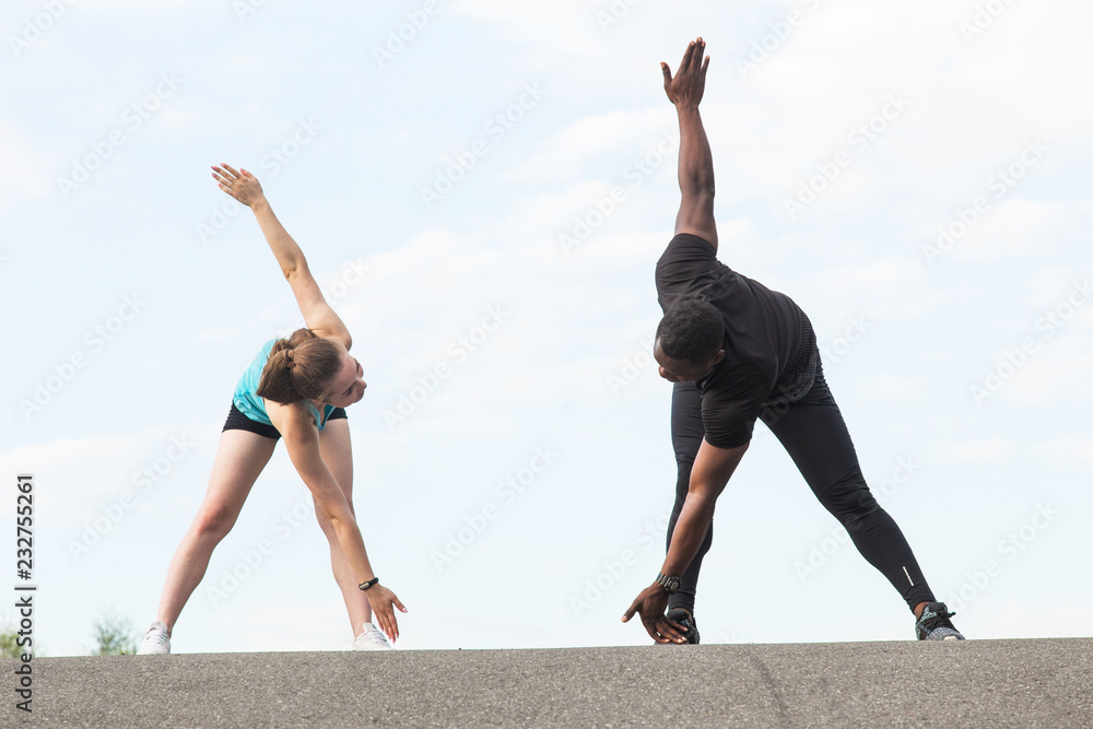 Obraz premium a pair of athletes do a warm-up. A loving couple an African American man and a European woman are sporting
