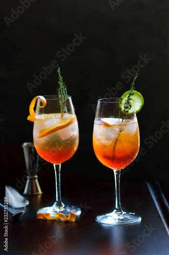 Aperol Stpritz,alcoholic cocktail with ice cubes and slices of orange at black background. Classic Italian aperitif beverage with cocktail accessories