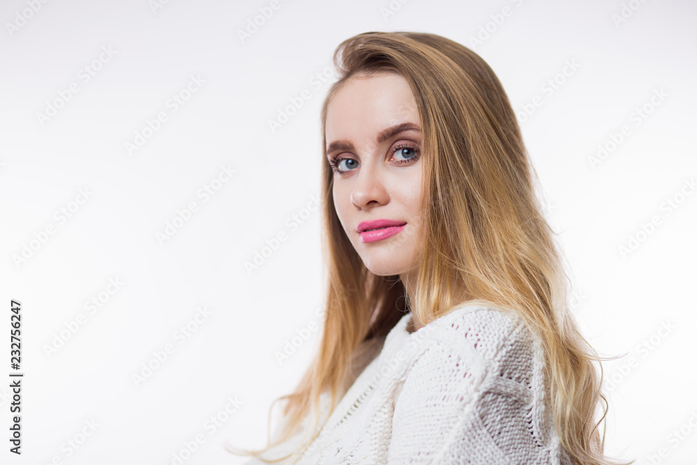 Horizontal closeup portrait of young blonde woman in beige knitted sweater on white background Horizontal closeup portrait of young blonde woman in beige knitted sweater on white background