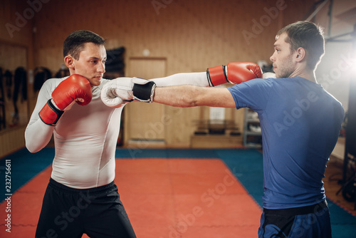 Two male kickboxers practicing on workout in gym