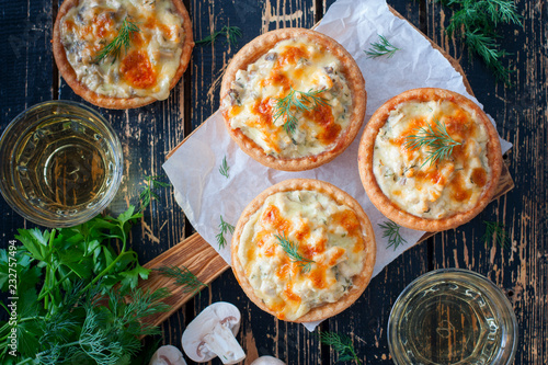 Hot appetizer - tartlets with mushrooms, chicken and cheese on a wooden table, top view, copy space