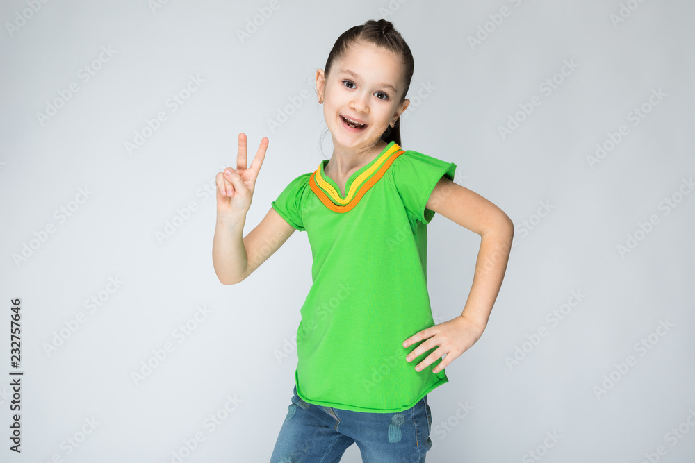 The girl on a gray background shows two fingers. The girl on a gray background shows two fingers.