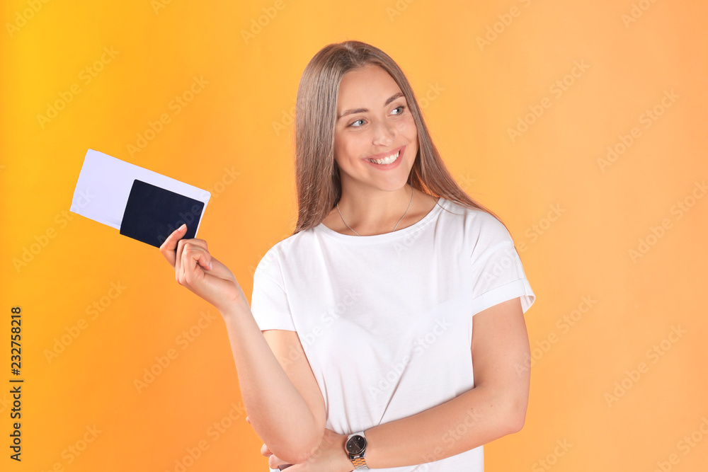 Excited young woman tourist standing isolated on yellow background holding passport with tickets. Excited young woman tourist standing isolated on yellow background holding passport with tickets.