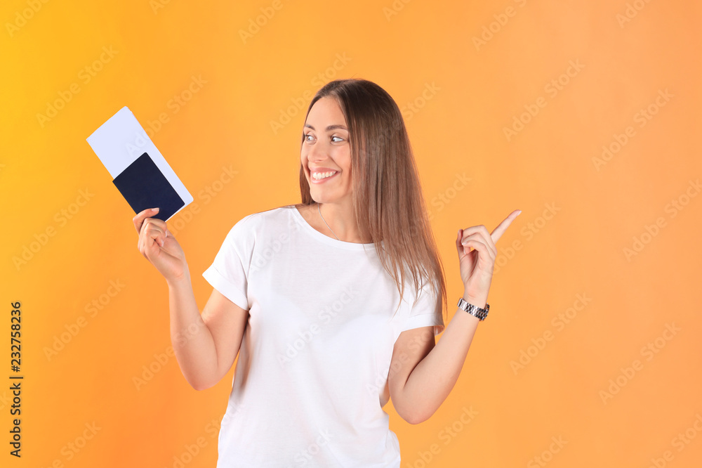 Excited young woman tourist standing isolated on yellow background holding passport with tickets. Excited young woman tourist standing isolated on yellow background holding passport with tickets.