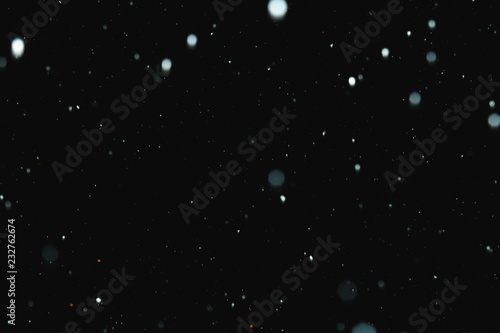 Flakes of snow falling on a black background. Isolated