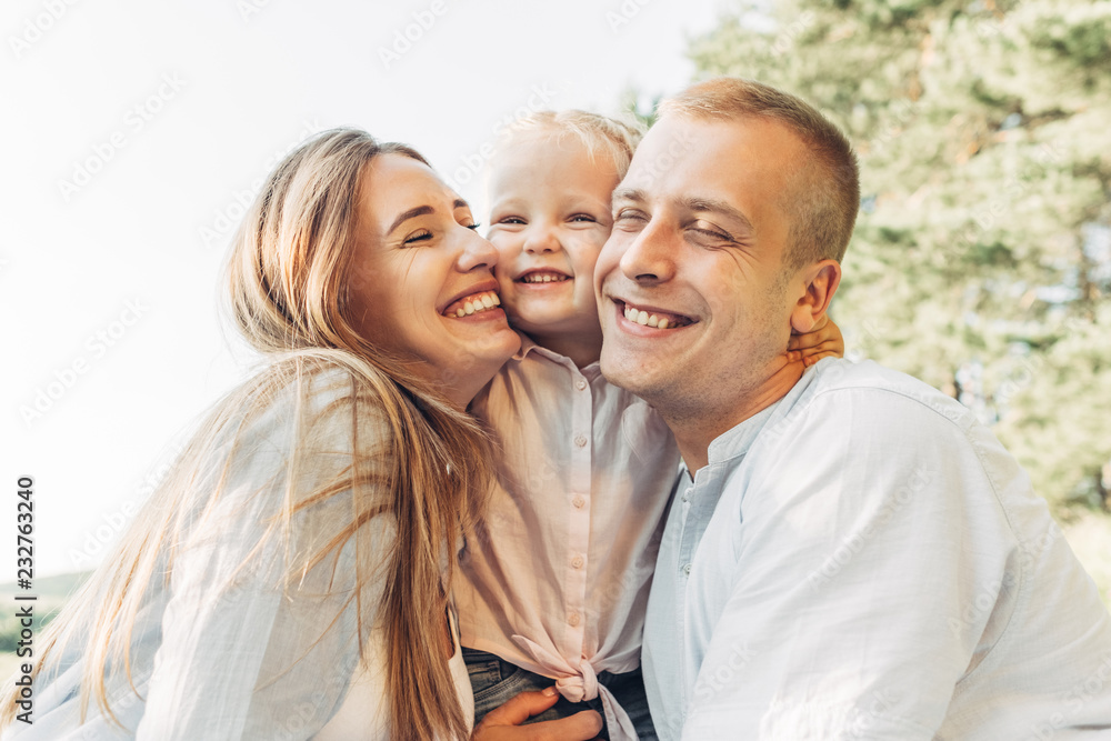 Young Adult Couple with Their Little Daughter Having Fun in the Park Outside the City, Family Weekend Picnic Concept, Three People Enjoying Summer Time Young Adult Couple with Their Little Daughter Having Fun in the Park Outside the City, Family Weekend Picnic Concept, Three People Enjoying Summer Time