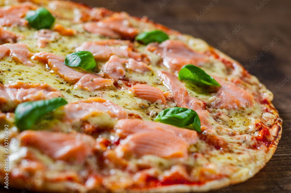 Pizza with Mozzarella cheese, salmon fish, tomato sauce. Italian pizza on wooden table background Pizza with Mozzarella cheese, salmon fish, tomato sauce. Italian pizza on wooden table background