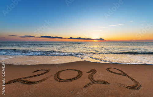 Number 2019 written on seashore sand at sunrise. Concept of upcoming new year and passing of time.