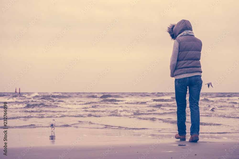 Woman walking on beach, autumn cold day