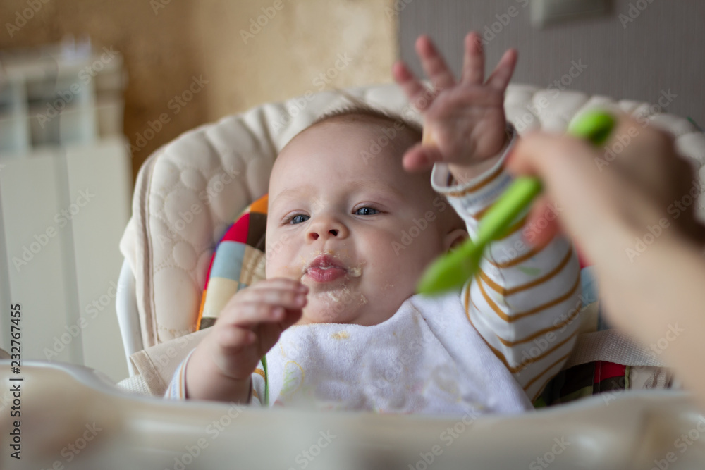 The first feeding of the baby from the spoon. Mom feeds baby homogenized chopped food with a spoon. child care. The first feeding of the baby from the spoon. Mom feeds baby homogenized chopped food with a spoon. child care.