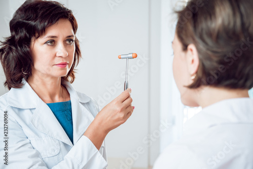 Neurological examination. The neurologist testing reflexes on a female patient using a hammer. photo