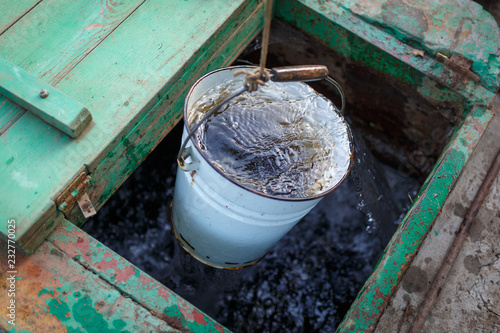 The full bucket of clear water rises from the deep well photo