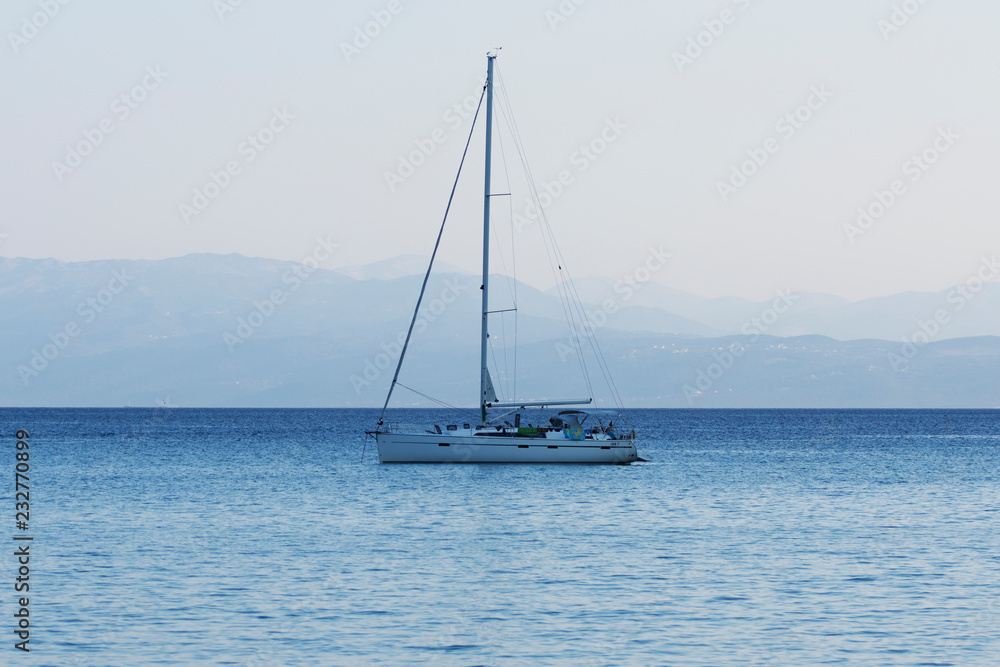 Small yacht sailing at dusk