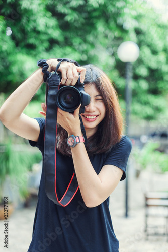 Beautiful and Happy Asian Woman holding Camera in the Garden. © biwwbbiw