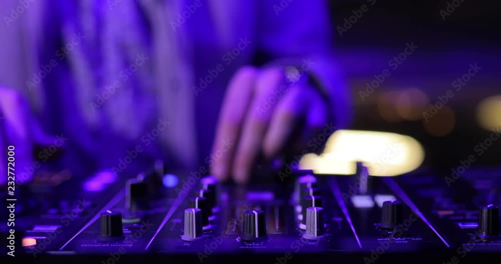Hands of DJ play music on the mixing console in a closeup