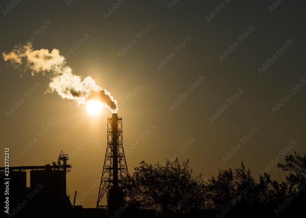 Factory chimney emits or discharges heavy smokes during sunset creating pollution. 