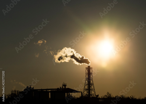 Factory chimney emits or discharges heavy smokes during sunset creating pollution. 