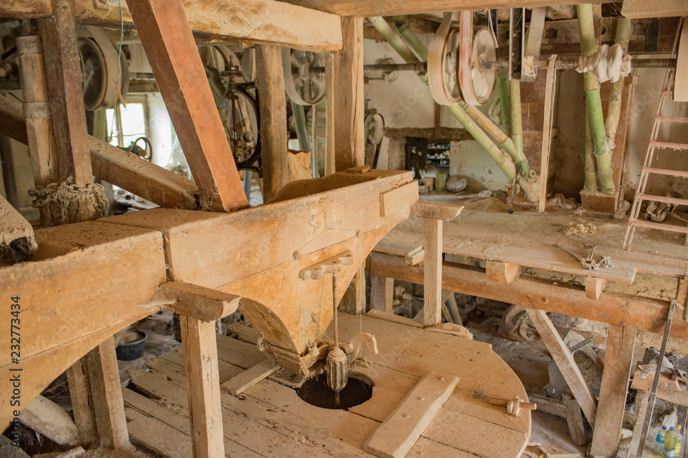 Traditional circular wooden flour mill equipment, viewed from side and mill equipment in background Traditional circular wooden flour mill equipment, viewed from side and mill equipment in background