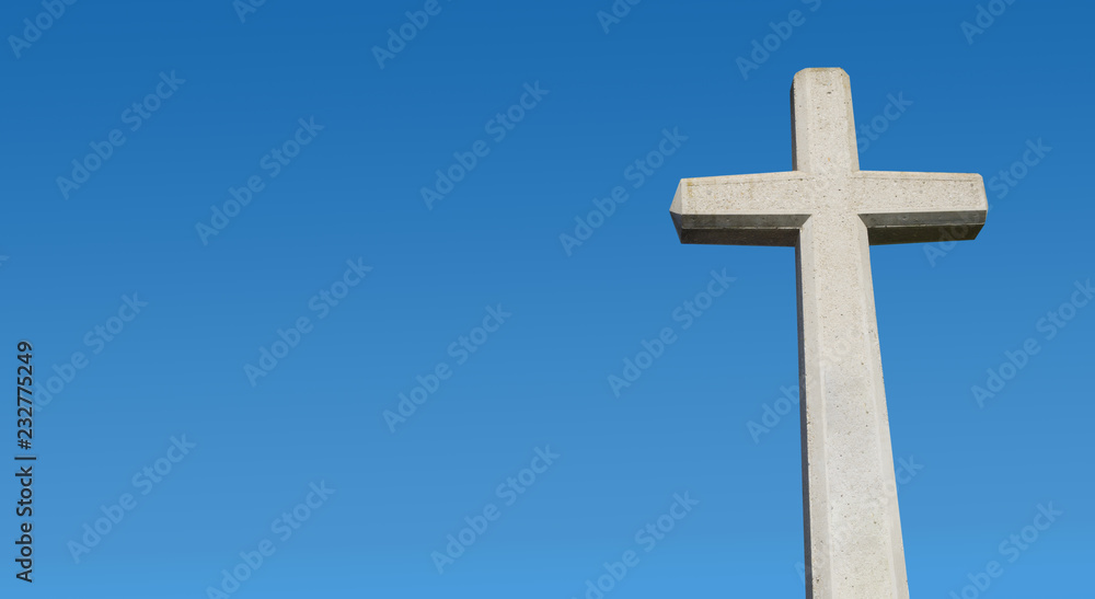 Kreuz aus Stein vor blauem Himmel