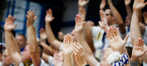 Sports fans cheer for the team. People greet athletes by raising their arms up.
