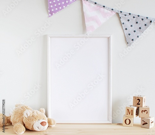 Fototapeta White frame mock up for photo, print art, text or lettering, with kids room decorations and toys. Blank frame on wooden table.