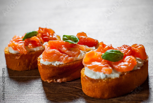 Canapes with smoked salmon and cream cheese on wooden table background