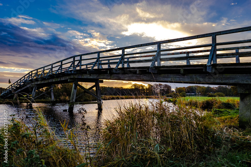 Landschaft mit Holzbrücke über kleinen Fluss