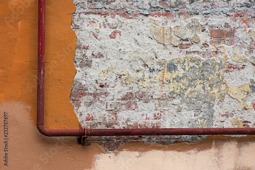 Old pipe on a worn wall of a building photo