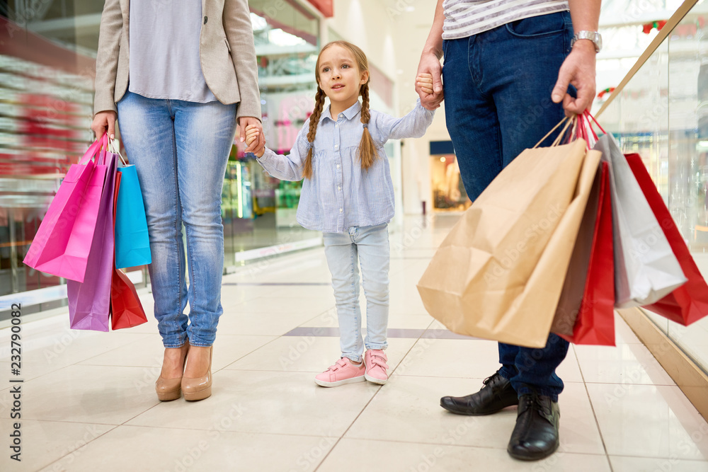 Portrait of happy family shopping in mall, focus on cute little girl holding hands with parents Portrait of happy family shopping in mall, focus on cute little girl holding hands with parents