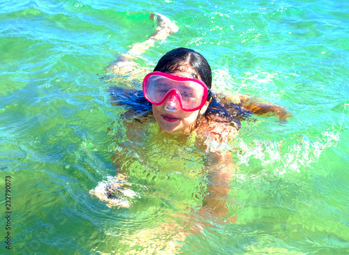 Happy child girl in a mask on the beach in summer