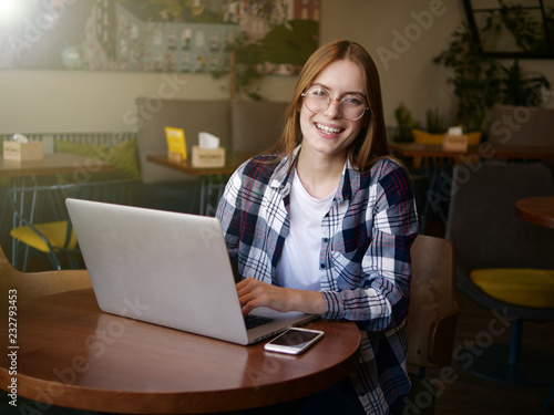 Beautiful girl sitting in a cafe and working behind a laptop