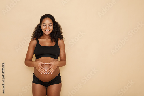 Foto Pregnant woman holding hands on her belly making a heart symbol